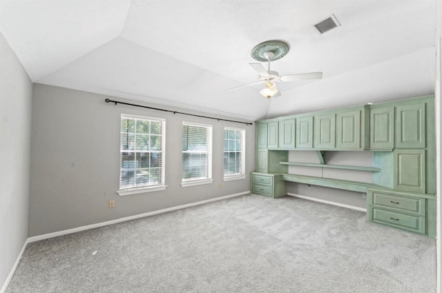 unfurnished bedroom featuring light colored carpet, ceiling fan, built in desk, and vaulted ceiling