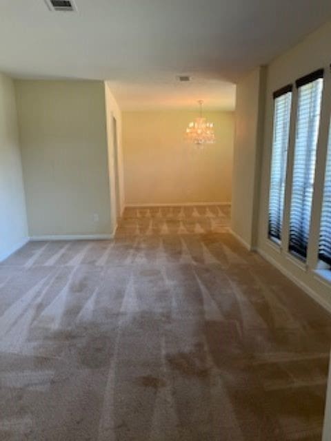 carpeted empty room with a chandelier