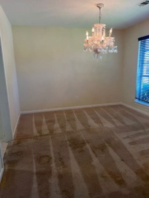 carpeted spare room featuring an inviting chandelier