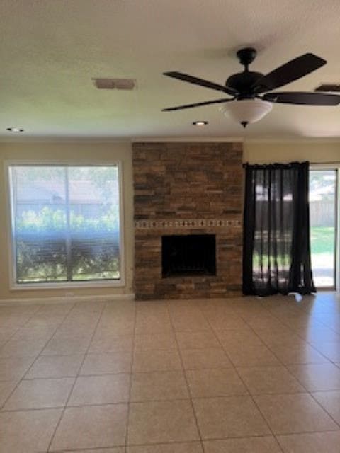 unfurnished living room with a fireplace, ceiling fan, and light tile patterned floors