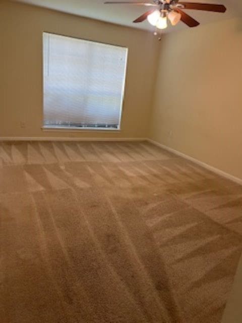 carpeted spare room featuring ceiling fan