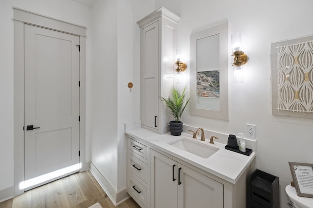 bathroom with hardwood / wood-style floors, vanity, and toilet