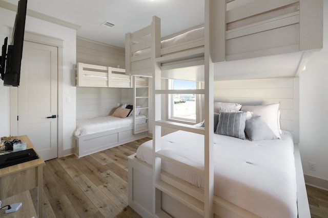 bedroom with wood walls and light hardwood / wood-style flooring