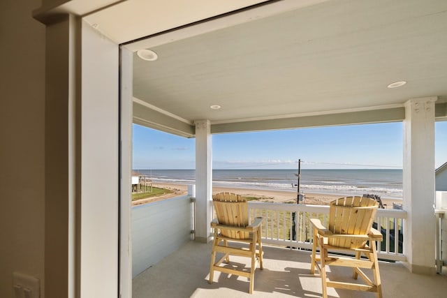 view of patio with a water view, a beach view, and a balcony