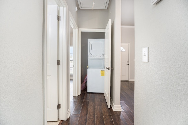 hallway with dark wood-type flooring, stacked washer and clothes dryer, and ornamental molding