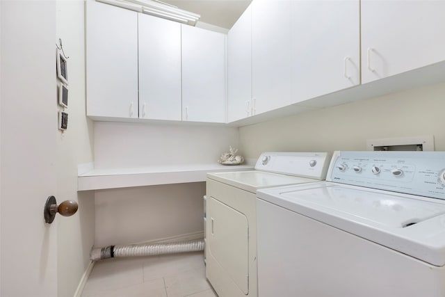 laundry room with cabinets, light tile patterned floors, and washer and clothes dryer