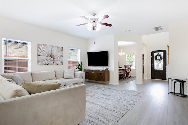 living room featuring ceiling fan with notable chandelier and light hardwood / wood-style floors