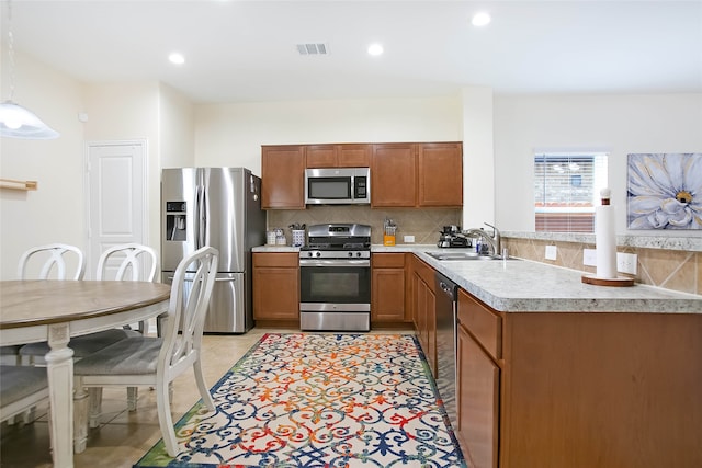 kitchen featuring backsplash, appliances with stainless steel finishes, decorative light fixtures, light tile patterned floors, and sink