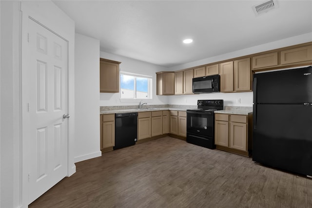 kitchen featuring black appliances, dark hardwood / wood-style floors, and sink