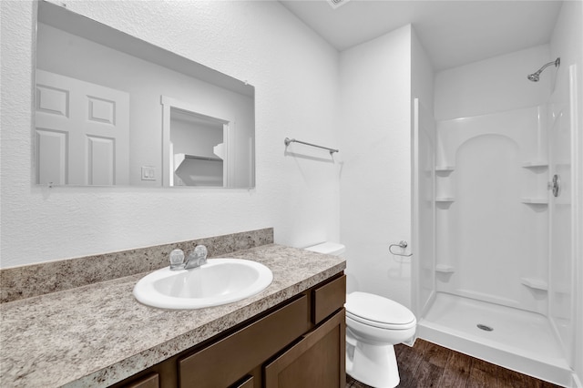 bathroom featuring hardwood / wood-style floors, walk in shower, vanity, and toilet