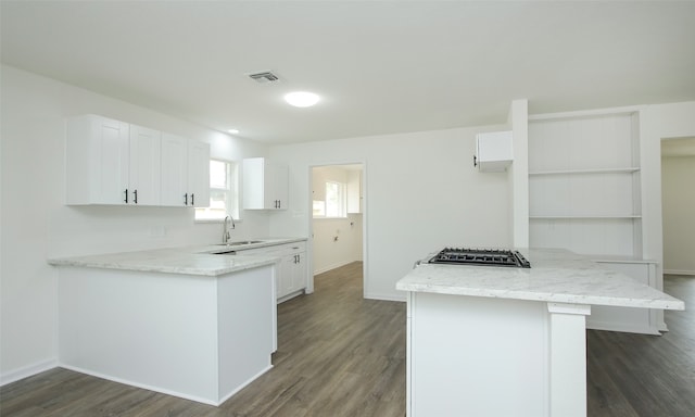 kitchen featuring a kitchen island, dark hardwood / wood-style floors, light stone countertops, white cabinets, and stainless steel gas cooktop