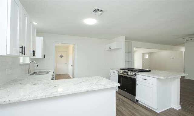 kitchen with hardwood / wood-style floors, kitchen peninsula, sink, stainless steel gas range, and white cabinetry