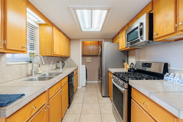 kitchen with decorative backsplash, sink, light tile patterned floors, appliances with stainless steel finishes, and washing machine and dryer