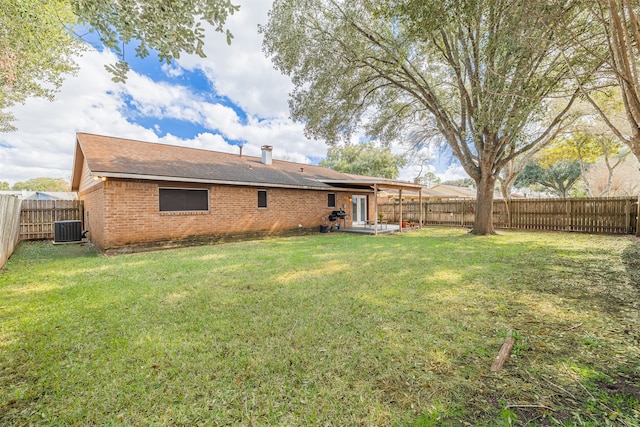 rear view of house with central AC unit and a yard