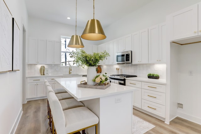 kitchen featuring stainless steel appliances, light hardwood / wood-style floors, white cabinets, and a center island