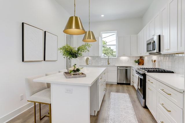 kitchen featuring sink, appliances with stainless steel finishes, a kitchen breakfast bar, a center island, and white cabinets