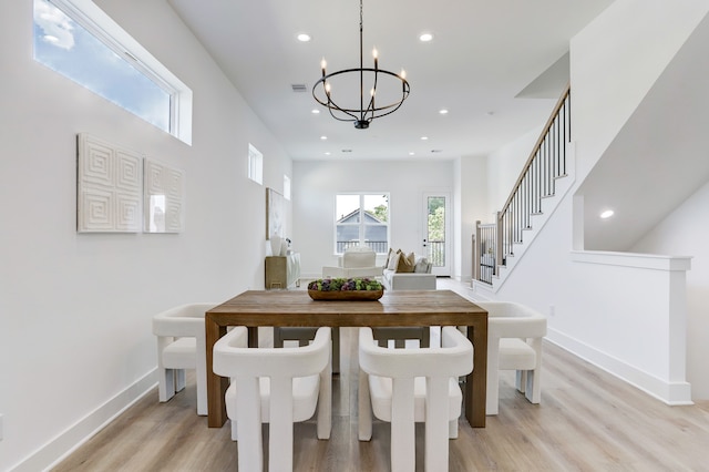 dining space featuring light wood-type flooring and an inviting chandelier