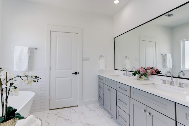 bathroom featuring a bath, vanity, and tile walls