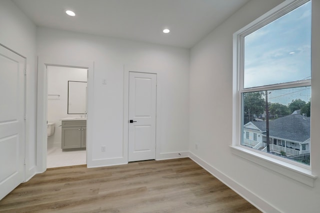 unfurnished bedroom featuring connected bathroom and light hardwood / wood-style flooring