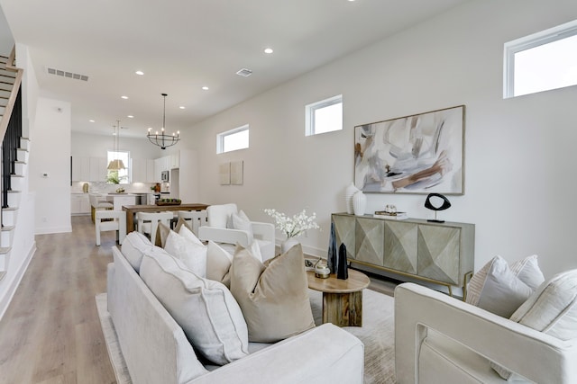 living room with a wealth of natural light, a notable chandelier, and light hardwood / wood-style floors