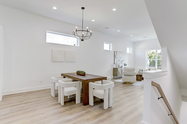 dining area with light hardwood / wood-style floors and a notable chandelier