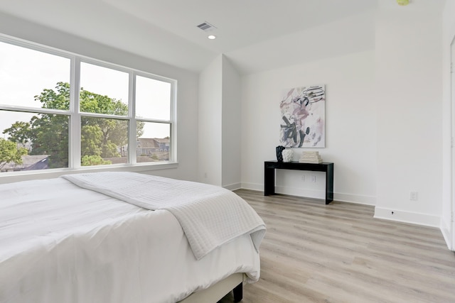 bedroom with vaulted ceiling and light hardwood / wood-style flooring