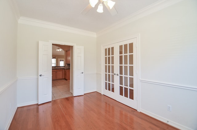 empty room featuring french doors, light hardwood / wood-style flooring, ceiling fan, and ornamental molding