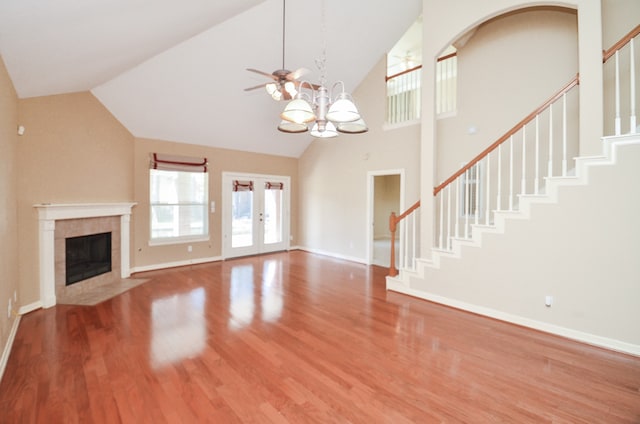 unfurnished living room featuring a tile fireplace, ceiling fan with notable chandelier, hardwood / wood-style flooring, and high vaulted ceiling