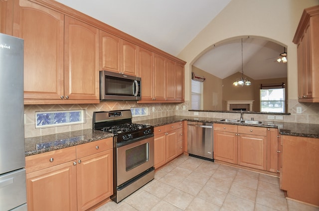 kitchen featuring sink, lofted ceiling, decorative backsplash, light tile patterned floors, and appliances with stainless steel finishes