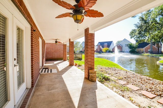 view of patio with a water view and ceiling fan