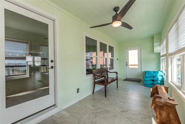 sunroom / solarium featuring ceiling fan, plenty of natural light, and wood ceiling