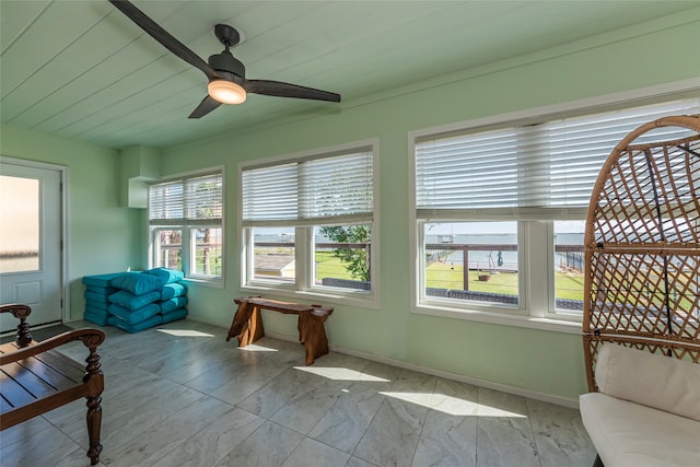 sunroom / solarium with a water view, ceiling fan, a healthy amount of sunlight, and wood ceiling