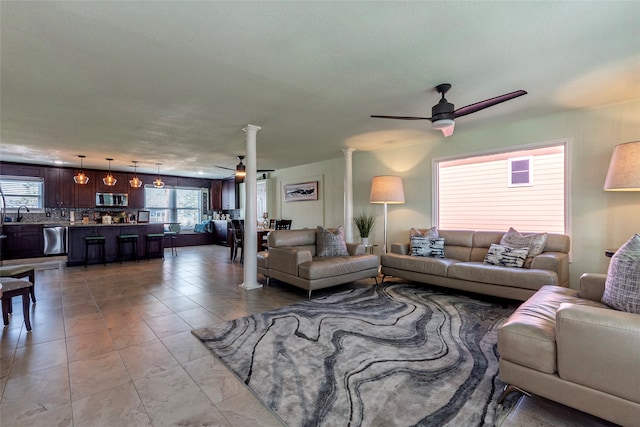 living room with ceiling fan, ornate columns, light tile patterned floors, and a textured ceiling