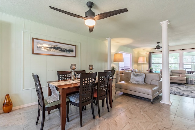 dining space with a textured ceiling, ceiling fan, and decorative columns