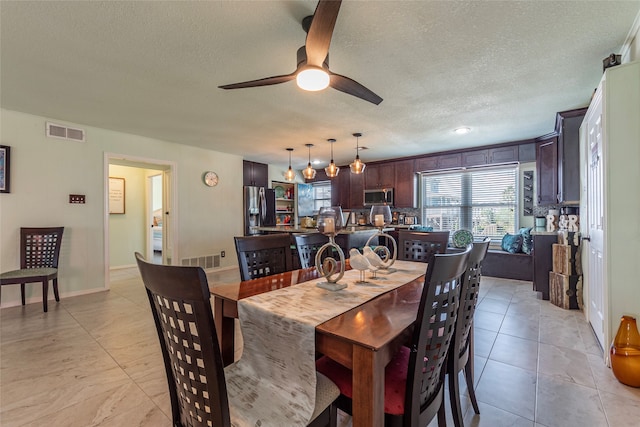 tiled dining area with ceiling fan and a textured ceiling