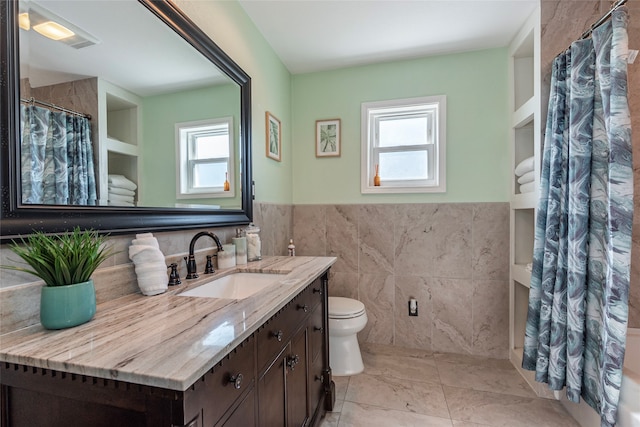 bathroom with vanity, built in shelves, walk in shower, and tile walls