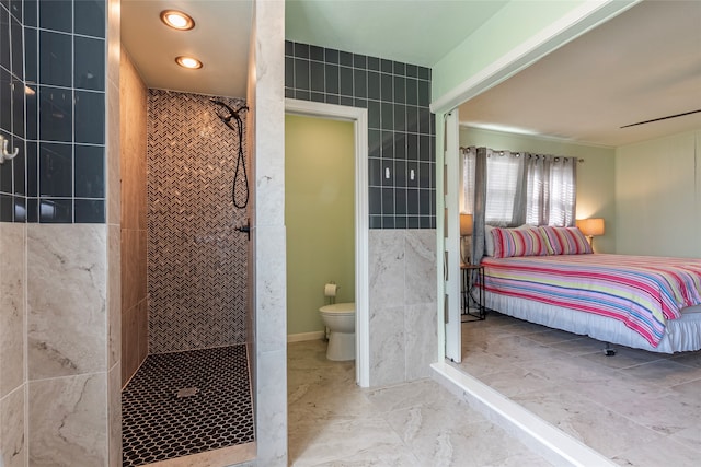 bathroom with a tile shower and toilet