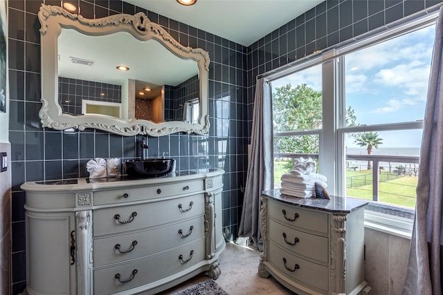 interior space featuring vanity, a water view, tile walls, and a healthy amount of sunlight