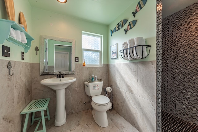 bathroom with tiled shower, tile patterned flooring, toilet, and tile walls