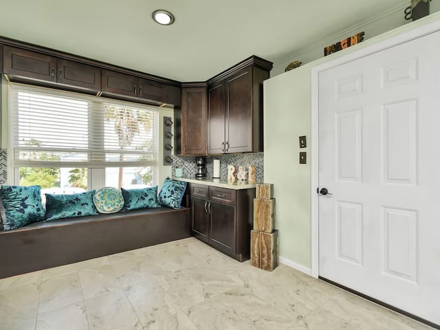 kitchen with decorative backsplash, dark brown cabinets, and ornamental molding