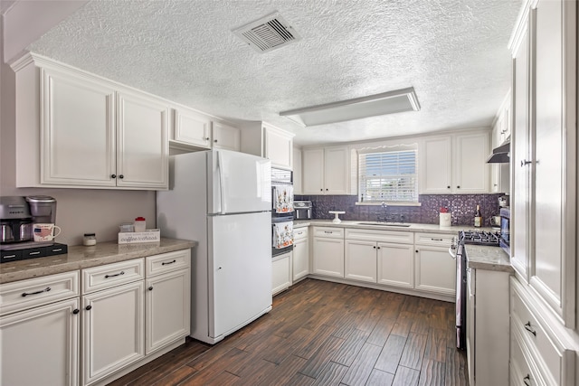 kitchen with sink, stainless steel stove, dark hardwood / wood-style floors, white fridge, and white cabinetry