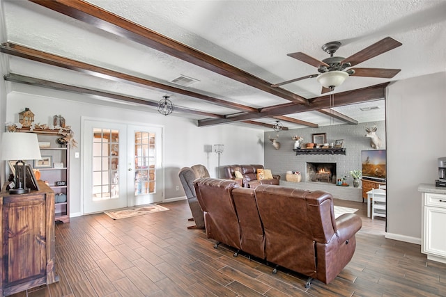 living room with french doors, a textured ceiling, beamed ceiling, dark hardwood / wood-style floors, and ceiling fan