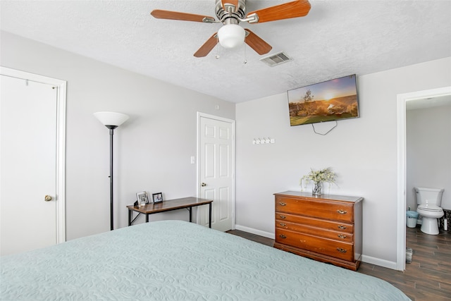 bedroom featuring ceiling fan, dark hardwood / wood-style floors, ensuite bath, and a textured ceiling