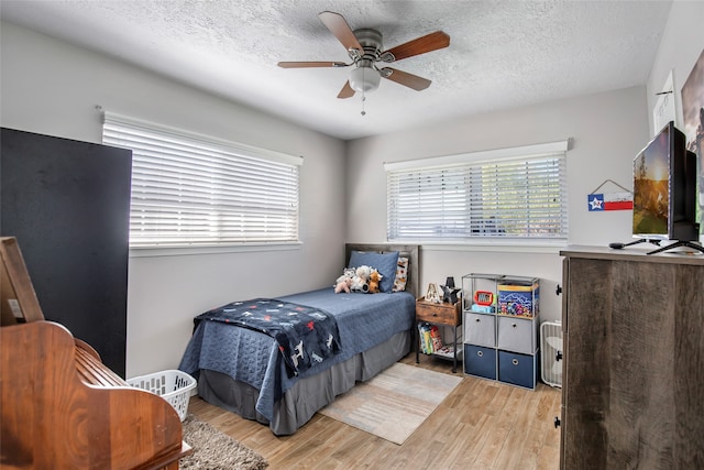 bedroom with a textured ceiling, hardwood / wood-style flooring, and ceiling fan