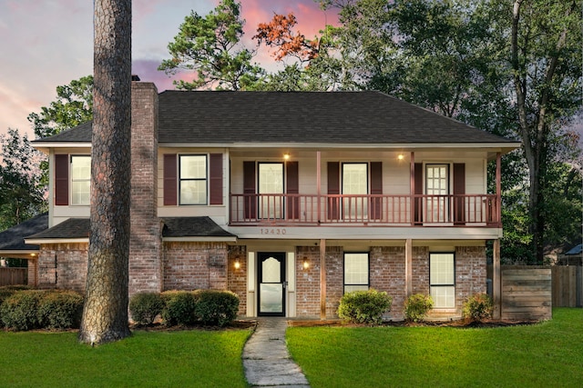 view of front of property with a balcony and a lawn