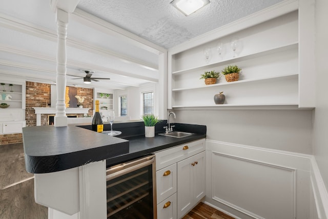 bar with white cabinetry, sink, dark wood-type flooring, wine cooler, and a textured ceiling