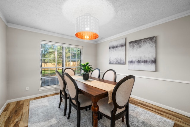 dining space featuring crown molding, hardwood / wood-style floors, a textured ceiling, and an inviting chandelier