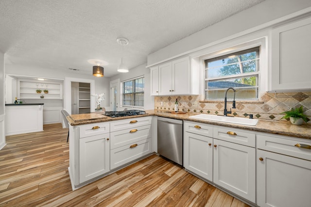 kitchen with kitchen peninsula, sink, hanging light fixtures, stainless steel dishwasher, and white cabinetry