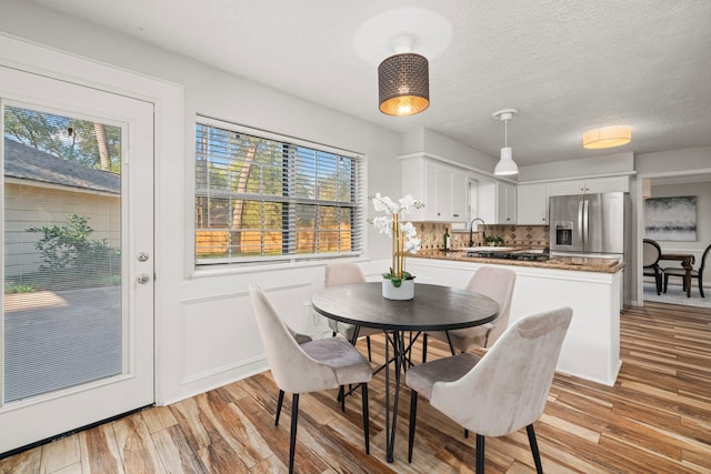 dining space with sink, a textured ceiling, and light wood-type flooring