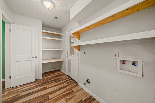 clothes washing area featuring electric dryer hookup, hookup for a washing machine, wood-type flooring, and a textured ceiling